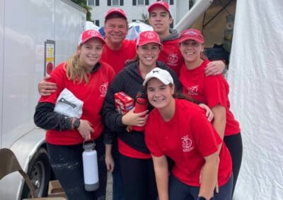 A group of people wearing red shirts and hats, standing together.